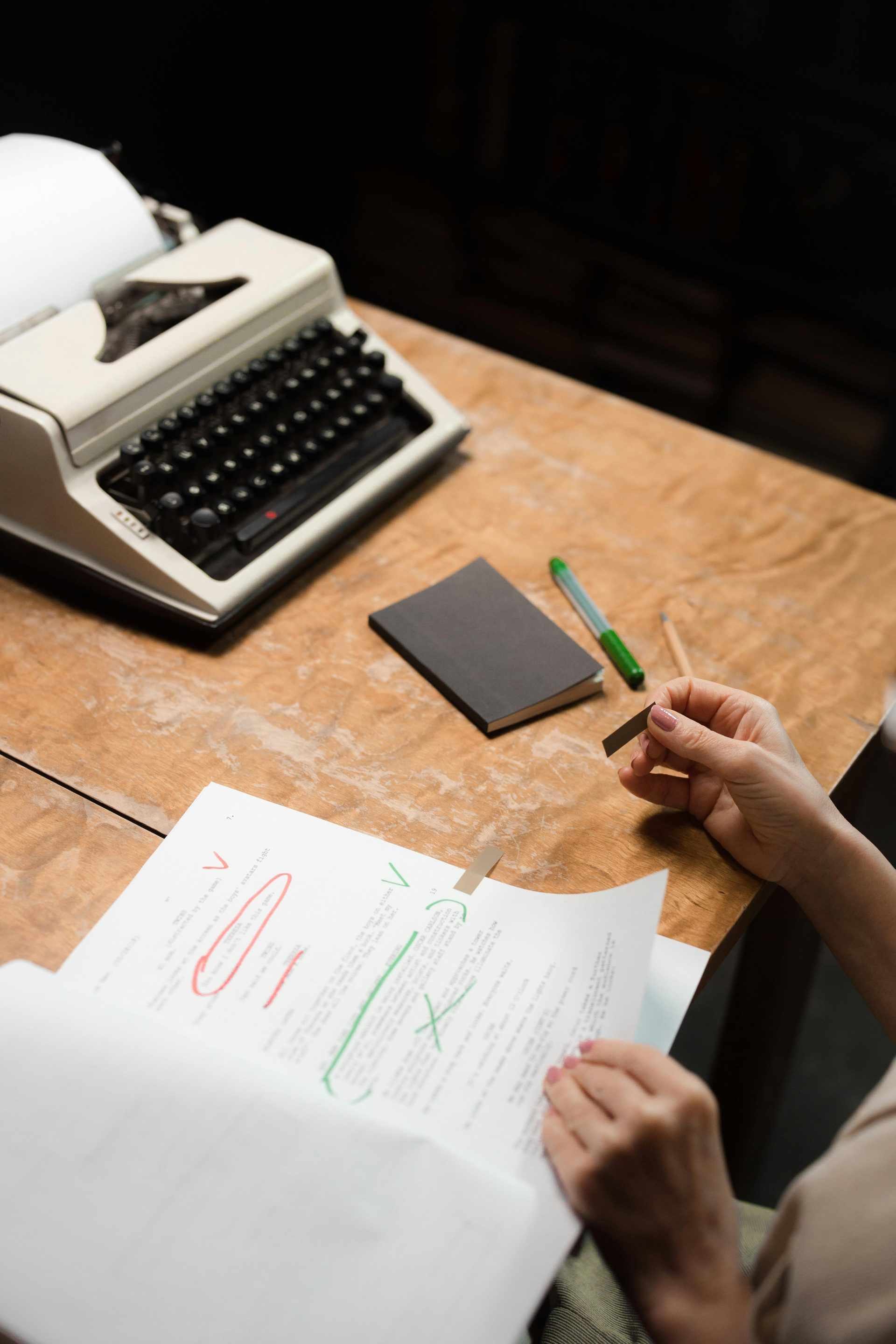 A person reviews a document at a desk with a retro typewriter, emphasizing office work in a vintage setting.